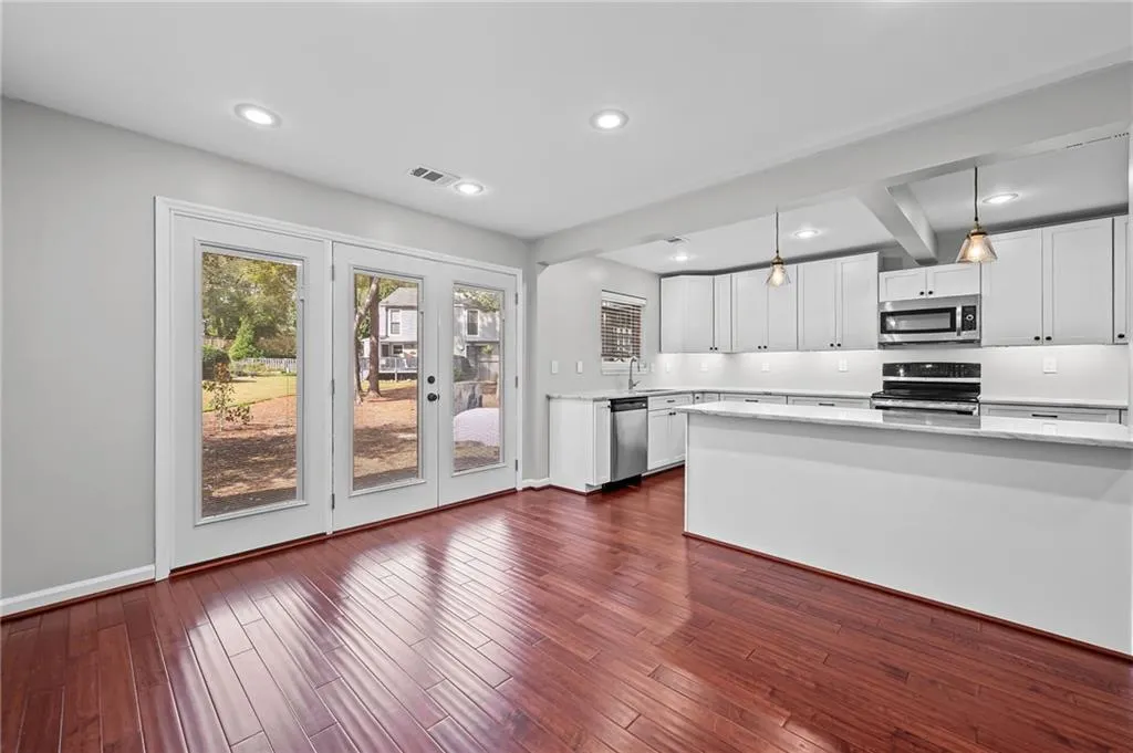Kitchen featuring white cabinetry, recessed lighting, stainless steel appliances, hanging light fixtures, and dark wood-type flooring