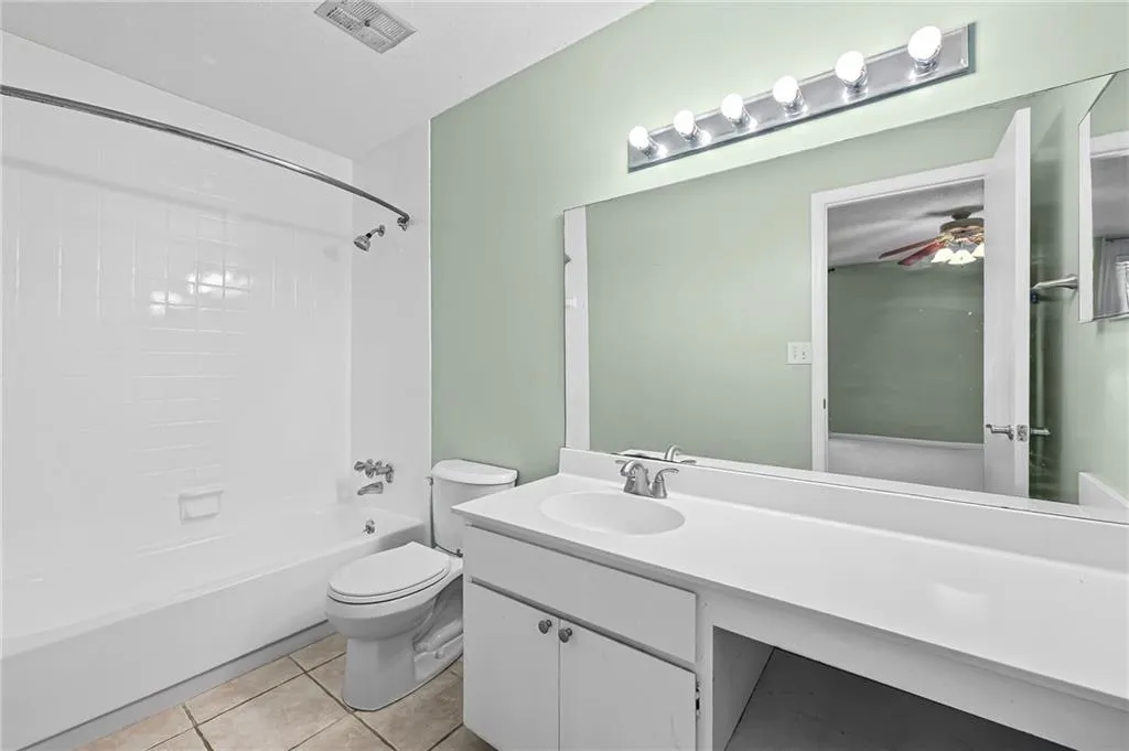 Full bathroom with bathing tub / shower combination, vanity, light tile patterned floors, and a ceiling fan