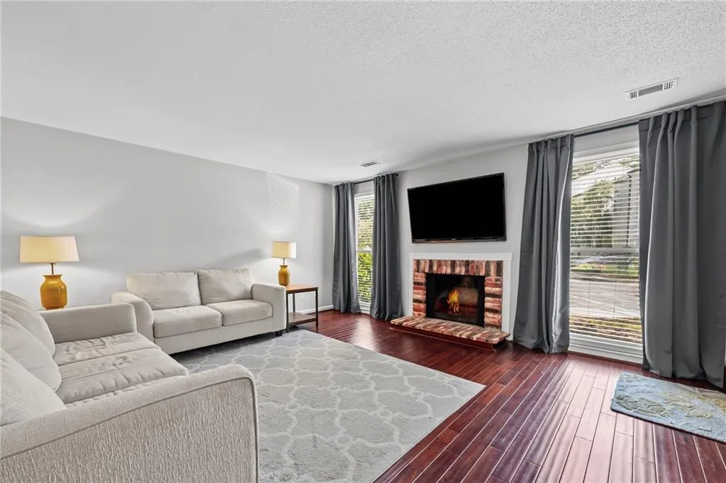 Living room with a fireplace, dark wood finished floors, and a textured ceiling