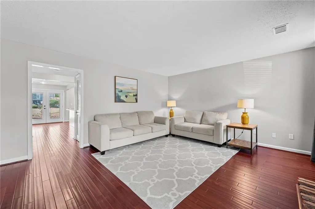 Living area featuring dark wood-style floors, french doors, and a textured ceiling