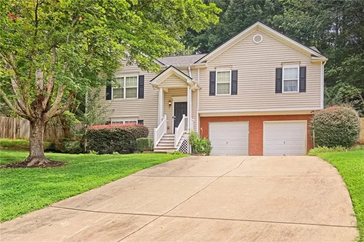 Traditional-style home featuring light-colored siding, black shutters, and a two-car garage with brick accents