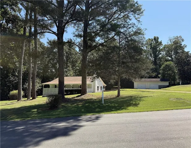 Expansive lawn surrounding a residence with a covered porch and a detached multi-car garage