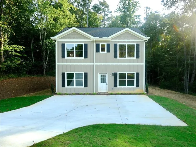 Two-story exterior with board and batten siding, decorative gable shingles, a gabled roofline, and contrasting black window shutters