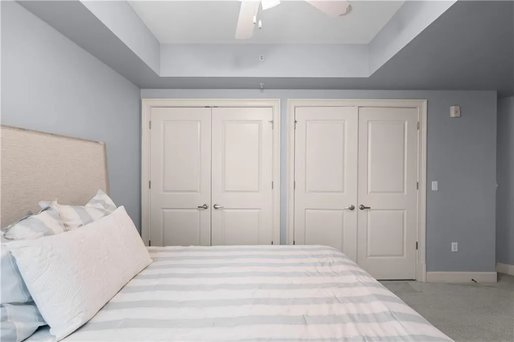 Bedroom featuring multiple closets, light carpet, and ceiling fan