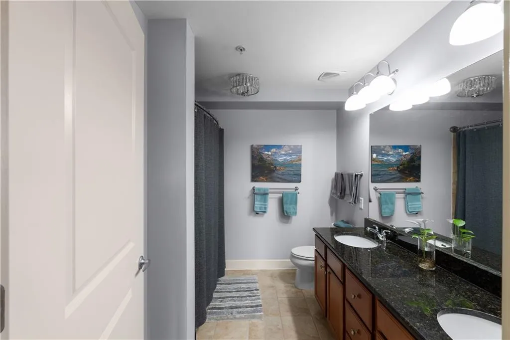 Full bathroom with double vanity, curtained shower, and light tile patterned flooring