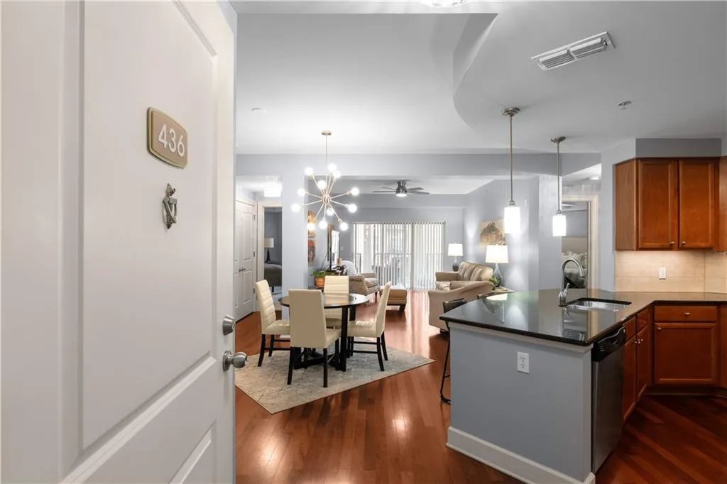 Kitchen with open floor plan, a peninsula, dark wood-style floors, hanging lights, and dark stone countertops