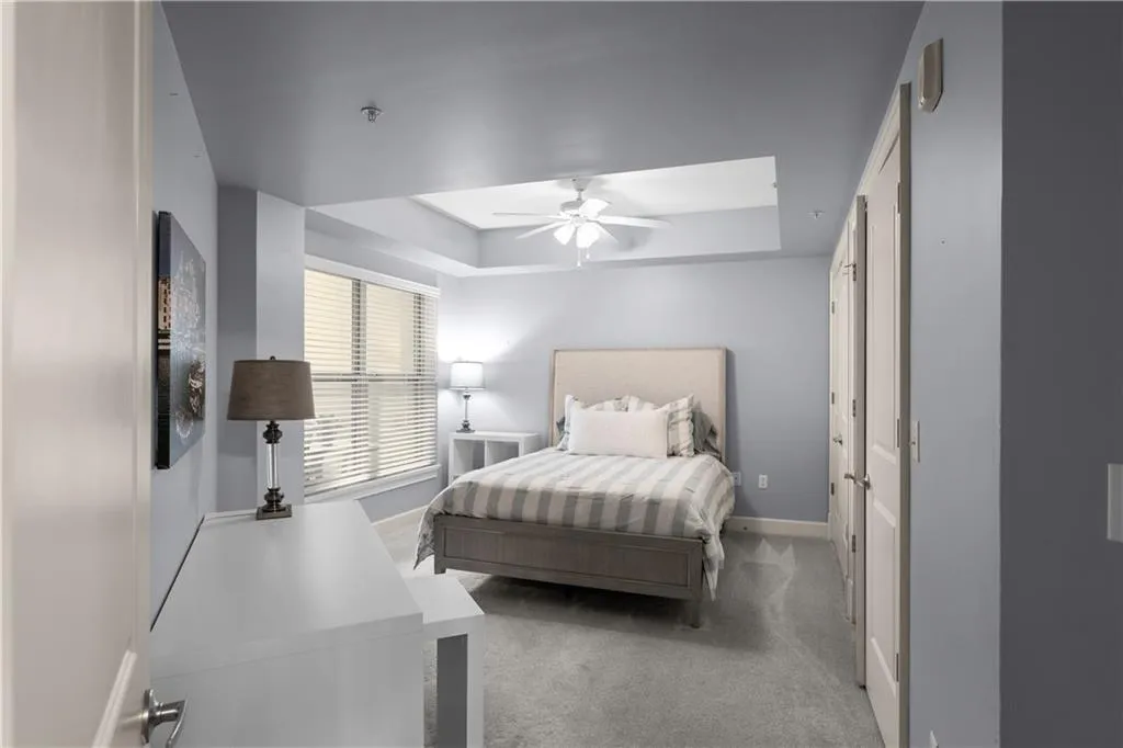 Carpeted bedroom featuring a tray ceiling and ceiling fan