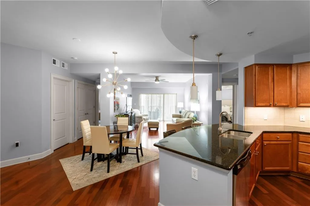 Kitchen with dark stone counters, open floor plan, a peninsula, suspended lighting, and dishwasher