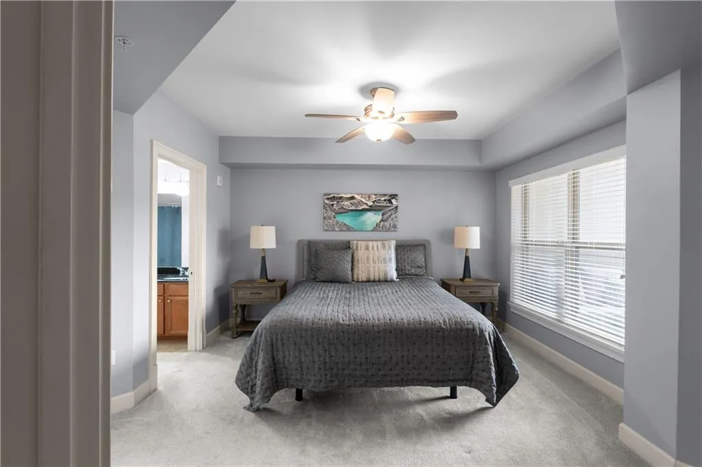 Bedroom with light colored carpet, multiple windows, and ensuite bath