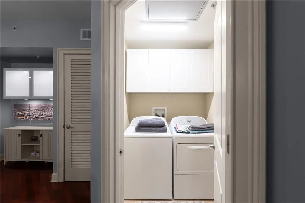 Laundry area featuring dark wood-style flooring, washer and dryer, and cabinet space