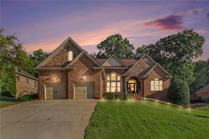 Brick and stone exterior with a two-car garage, multiple gables, and a concrete driveway