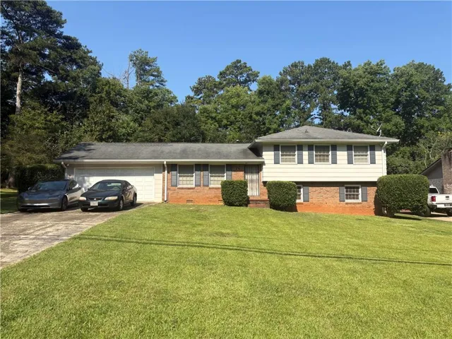 Split-level residence featuring a brick and siding exterior, an attached two-car garage, and a concrete driveway
