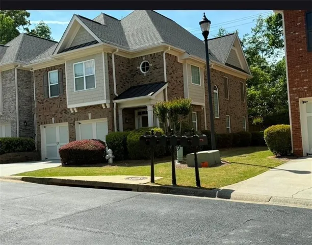 Brick exterior with gabled roofs, multiple windows, and an attached garage