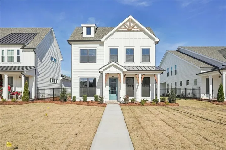 Contemporary farmhouse-style residence featuring white siding, dark-framed windows, and a prominent front porch with exposed timber accents