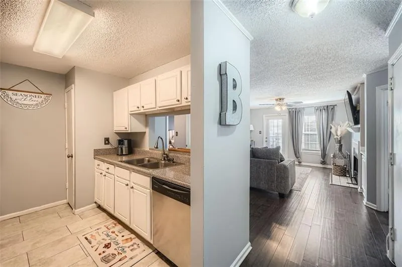 Kitchen featuring white cabinets, stainless steel dishwasher, a textured ceiling, ceiling fan, and open floor plan