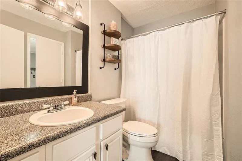 Full bath featuring vanity, a shower with curtain, and a textured ceiling