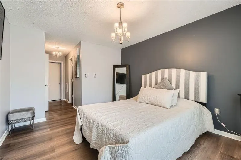 Bedroom featuring a chandelier, dark wood-style floors, and a textured ceiling