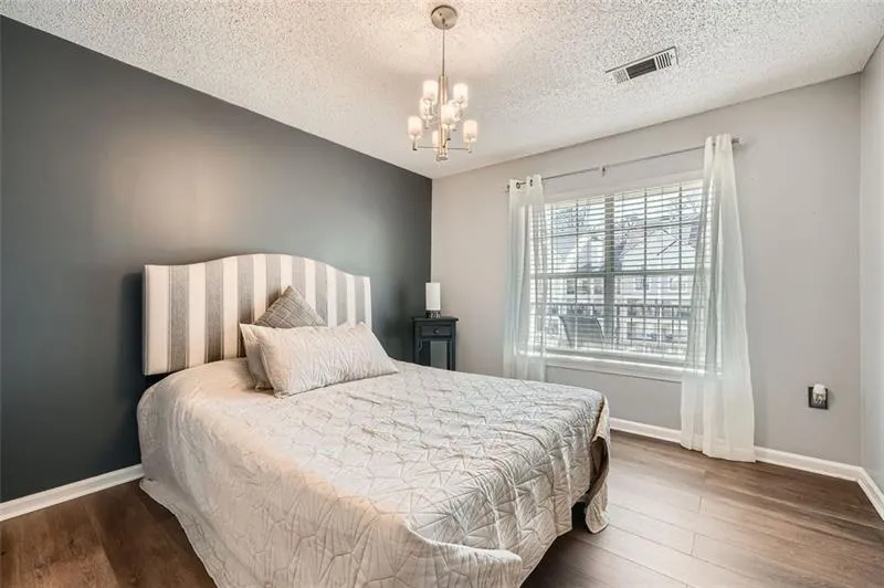 Bedroom featuring wood finished floors, a chandelier, and a textured ceiling