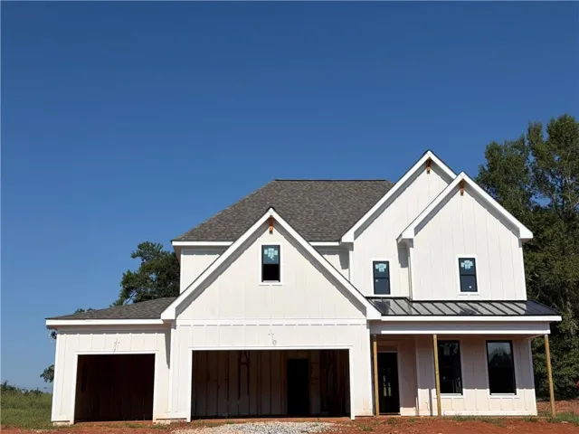 Two-story exterior with board and batten siding, dark-framed windows, a covered entry, a metal roof accent, and a two-car garage