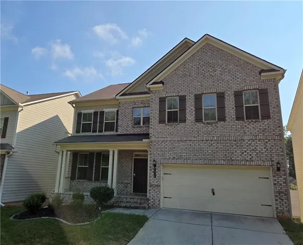 Brick and siding exterior with a covered front porch, attached two-car garage, and established landscaping