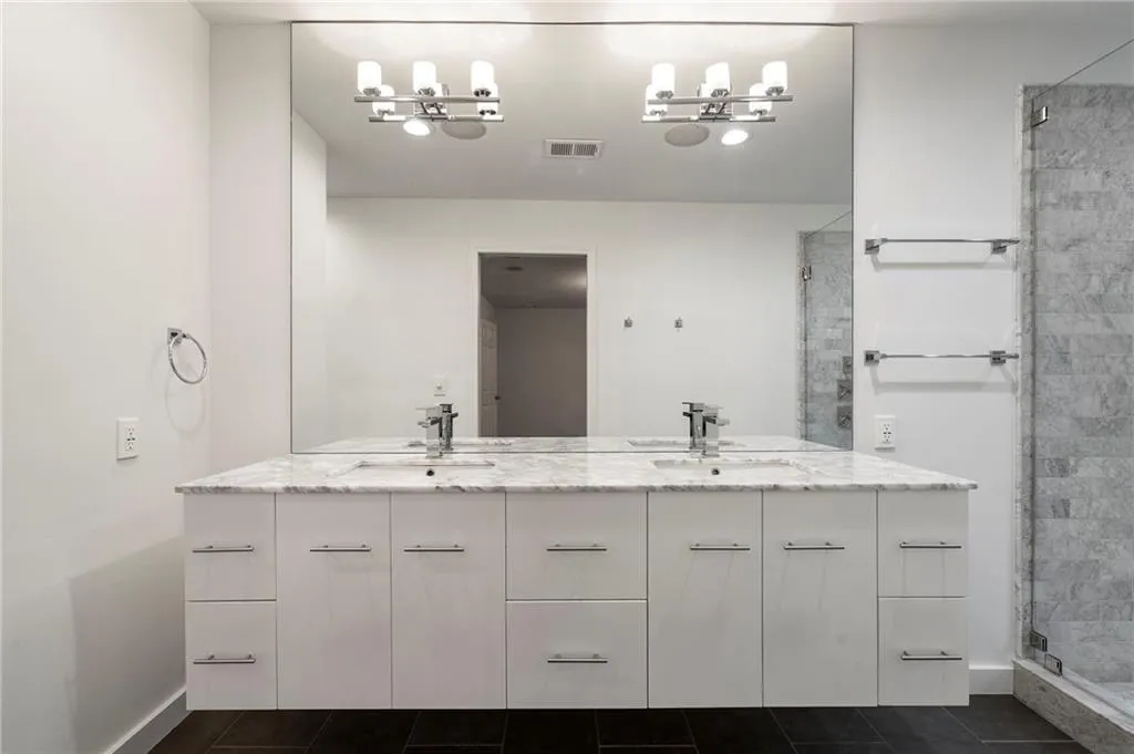 Primary bath features a double vanity, a stall shower, and tile patterned floors