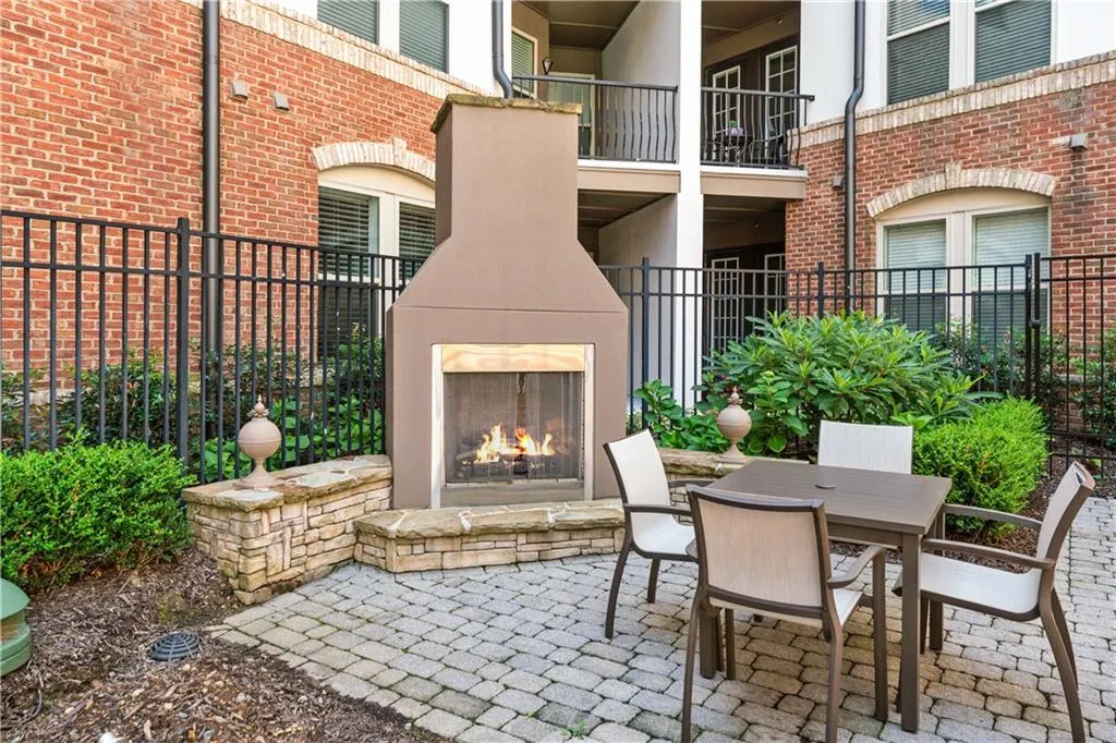 View of patio with a lit fireplace and outdoor dining space