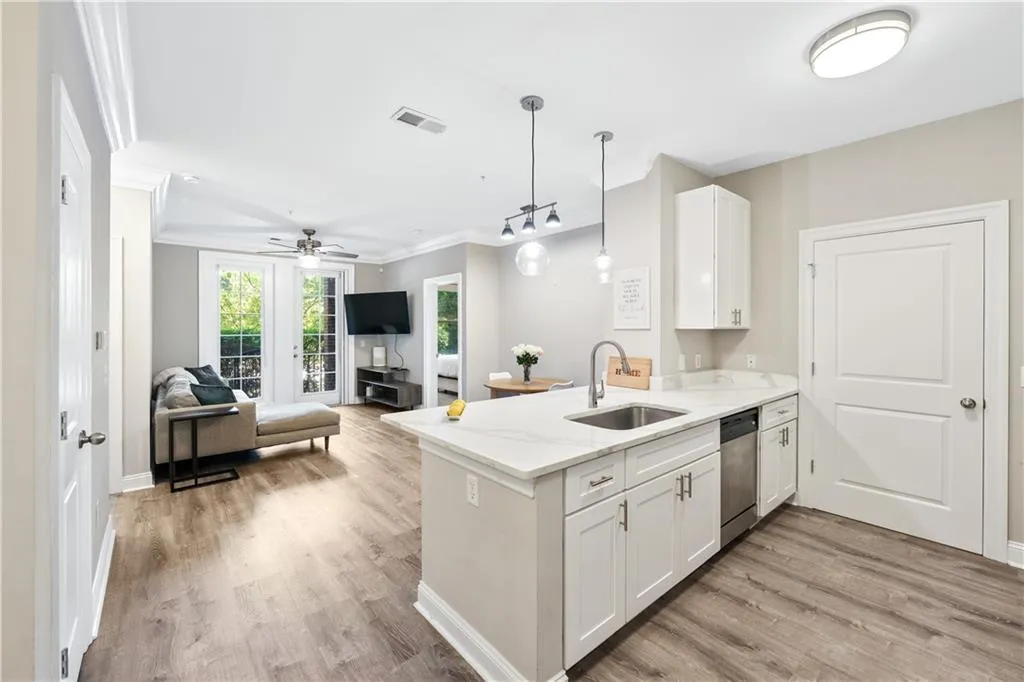 Kitchen featuring white cabinetry, light stone counters, hanging light fixtures, light wood-style flooring, and ornamental molding