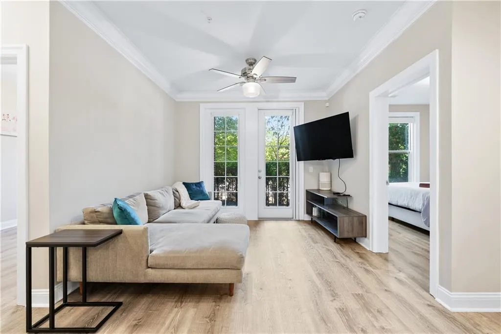 Living area with crown molding, light wood-style floors, a ceiling fan, and french doors and avalanches of natural light