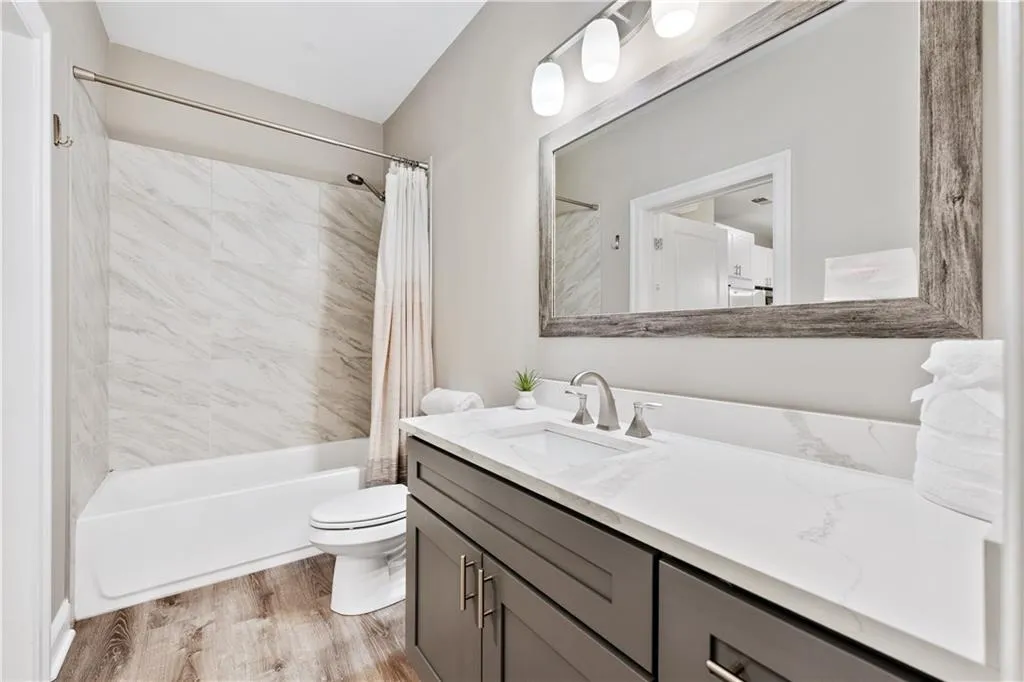 Bathroom featuring shower / bath combo with shower curtain, vanity, and light wood-style flooring