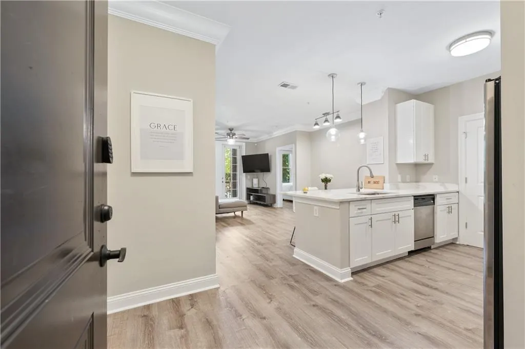 Kitchen featuring open floor plan, a peninsula, ceiling fan, hanging light fixtures, and white cabinets