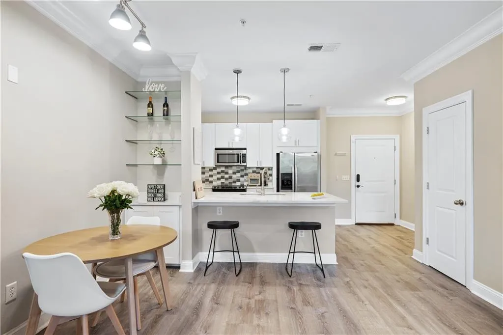 Kitchen with a peninsula, white cabinets, decorative backsplash, crown molding, and appliances with stainless steel finishes