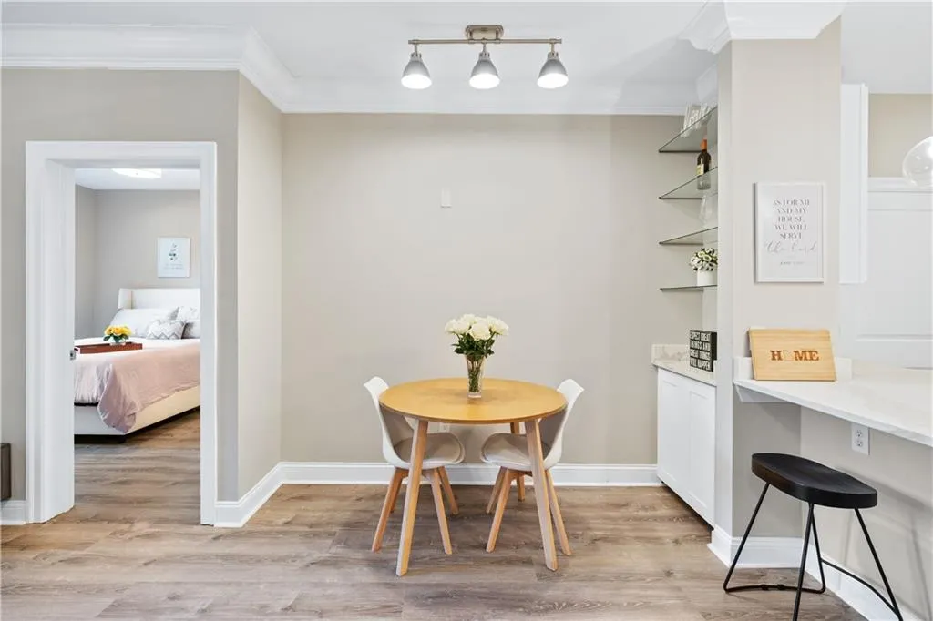 Dining room with light wood-style floors and ornamental molding. Glass shelves decorative nook.