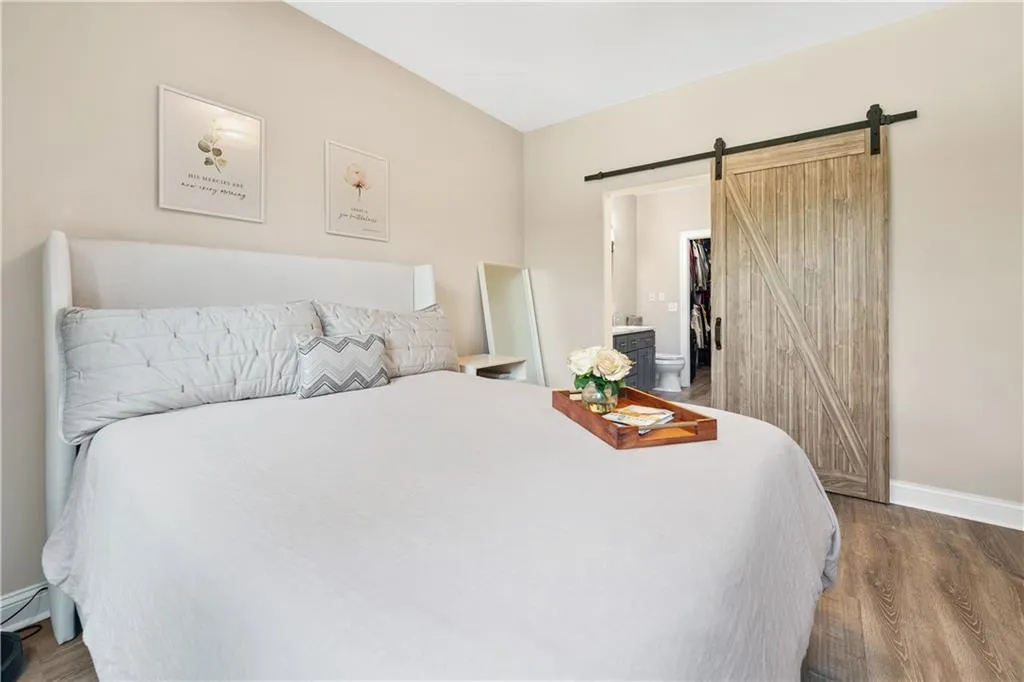 Bedroom featuring light wood-style flooring, ensuite bath, and a sliding barn door