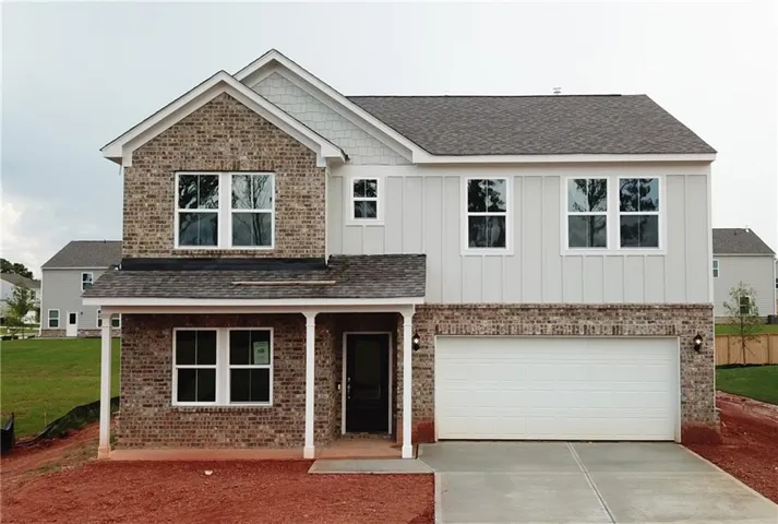 Two-story residence featuring brick and vertical siding, a covered front porch, an attached garage, and a concrete driveway
