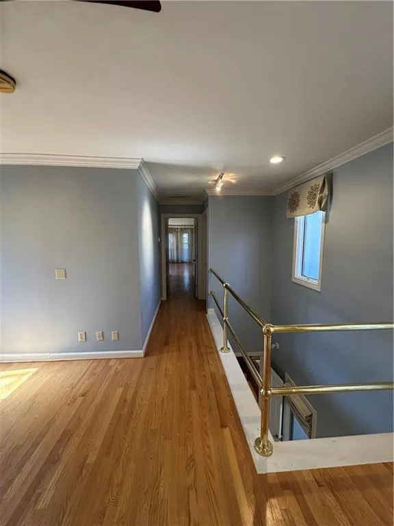 Corridor with crown molding, baseboards, an upstairs landing, recessed lighting, and wood finished floors