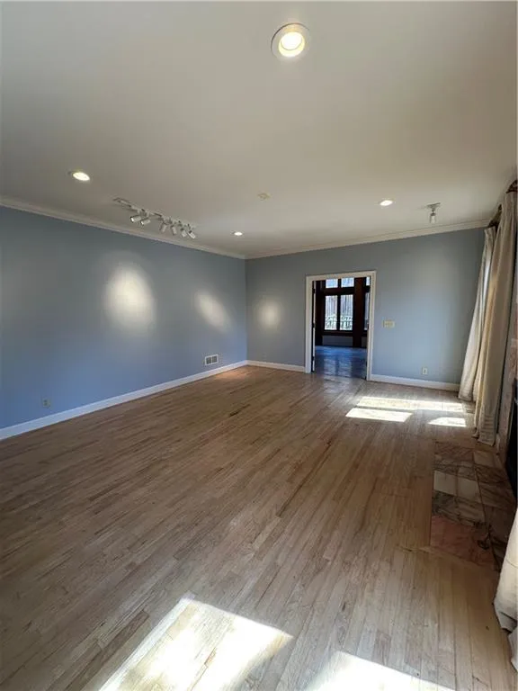 Unfurnished living room with visible vents, baseboards, ornamental molding, recessed lighting, and wood finished floors