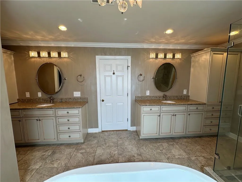 Bathroom featuring two vanities, ornamental molding, and a sink