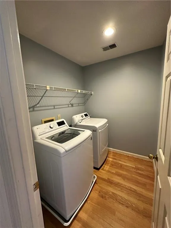 Laundry area with visible vents, light wood finished floors, baseboards, laundry area, and separate washer and dryer
