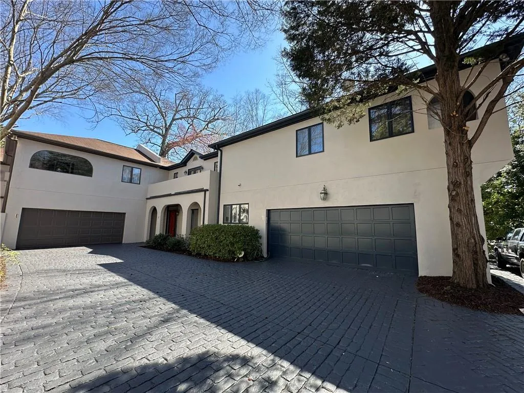 View of front facade with stucco siding, decorative driveway, and an attached garage