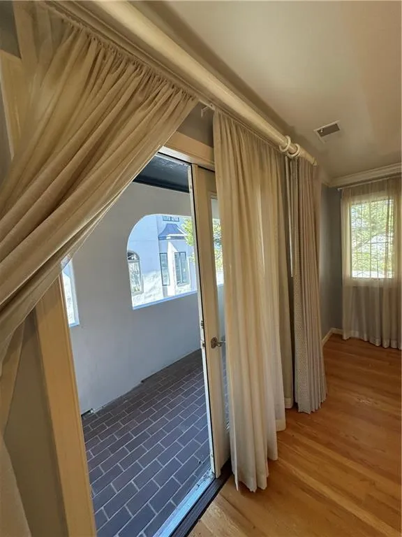 Additional living space with vaulted ceiling, wood finished floors, and visible vents