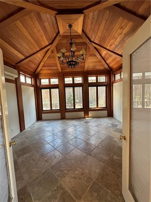 Unfurnished sunroom with a notable chandelier, wooden ceiling, an AC wall unit, and vaulted ceiling