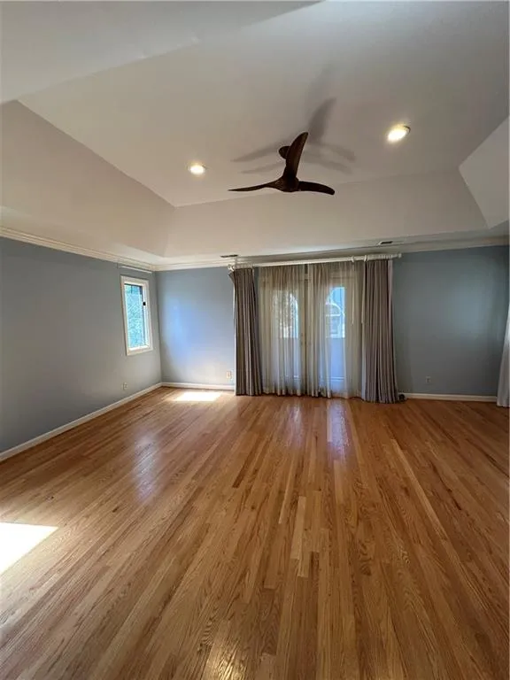 Spare room with wood finished floors, baseboards, a tray ceiling, recessed lighting, and ceiling fan