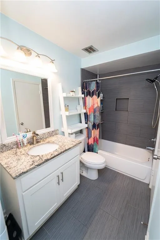 Bathroom with shower / bath combination with curtain, visible vents, toilet, and vanity