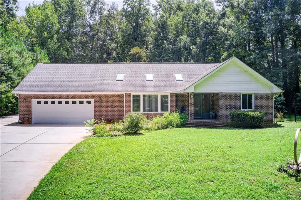 Ranch-style home featuring a garage and a front lawn