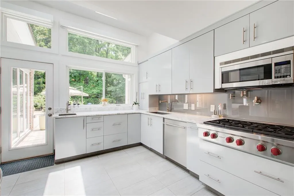 Kitchen with tasteful backsplash, light tile patterned floors, light stone counters, appliances with stainless steel finishes, and sink