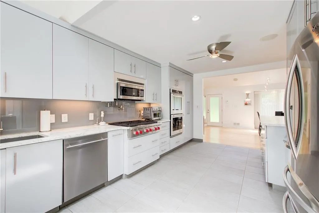 Kitchen featuring tasteful backsplash, ceiling fan, stainless steel appliances, light stone counters, and light hardwood / wood-style floors