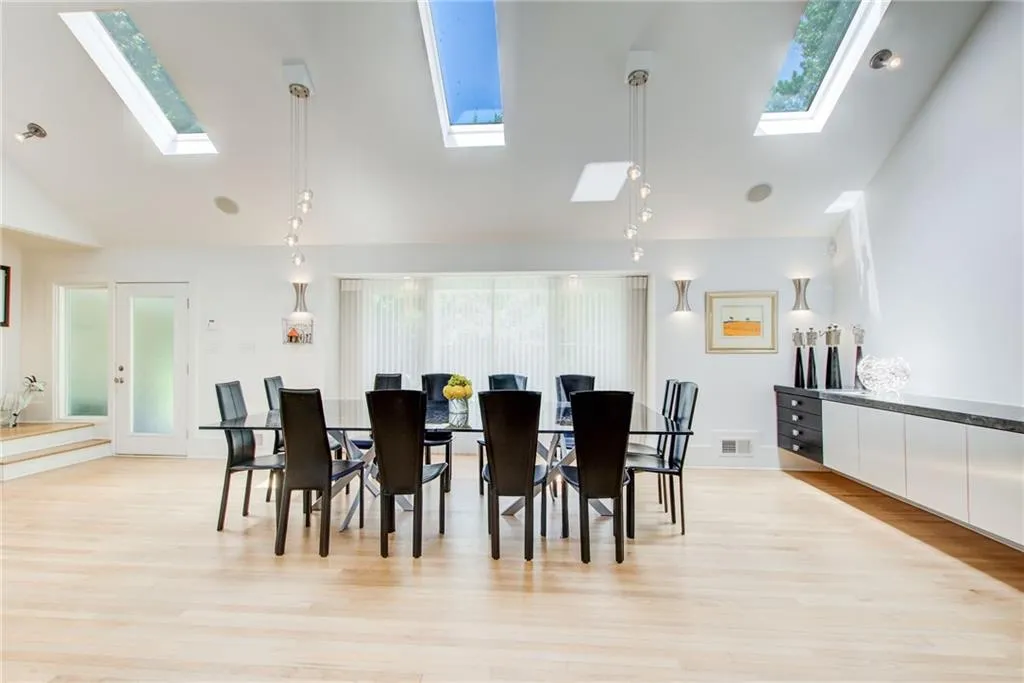 Dining space featuring lofted ceiling with skylight and light hardwood / wood-style flooring