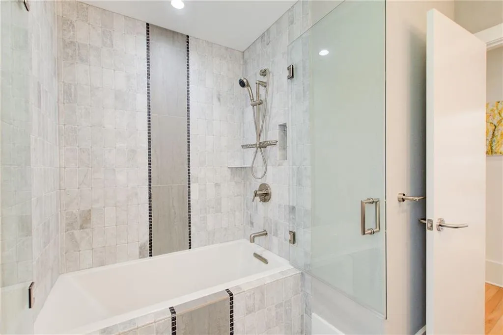 main level full bath tub/shower with frameless glass door and gorgeous tile.