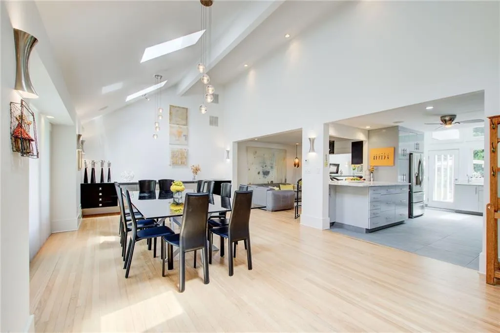 Dining room with a skylight, light hardwood / wood-style flooring, ceiling fan, beamed ceiling, and high vaulted ceiling