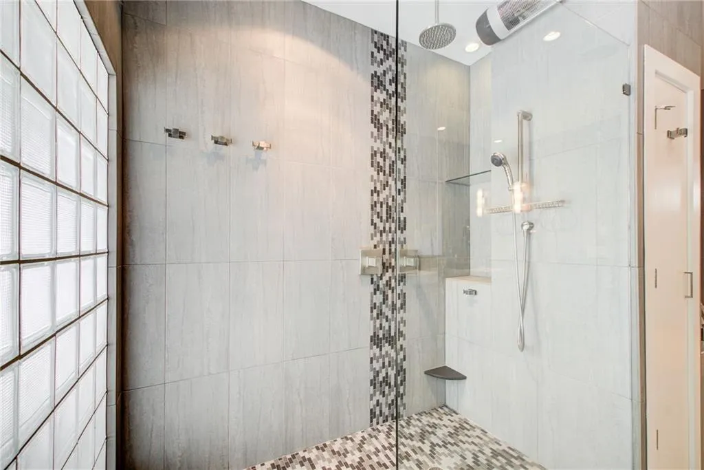 Two shower heads, frameless panel, natural light and even a heater.